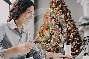 Happy young woman doing online shopping on laptop computer at home during Winter holidays sales