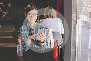 Happy young woman drinking cappuccino, latte, macchiato, tea, using tablet computer and talking on the phone in a coffee shop / ba