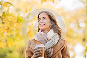 Happy young woman drinking coffee in autumn park