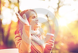 Happy young woman drinking coffee in autumn park