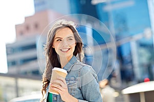 Happy young woman drinking coffee on city street