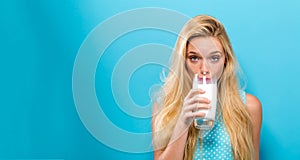 Happy young woman drinking milk on a solid background