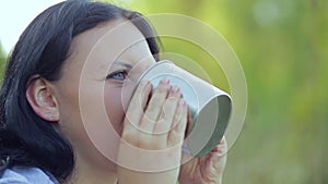 Happy young woman drinks from mug tea.