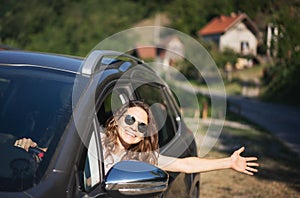 Happy young woman driver driving car on country road