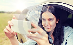 Happy young woman driving in car with smartphone