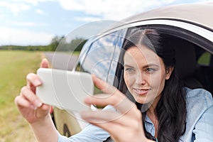 Happy young woman driving in car with smartphone