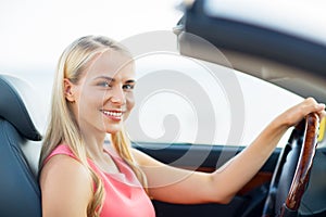 Happy young woman driving convertible car