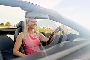 Happy young woman driving convertible car