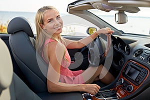 Happy young woman driving convertible car