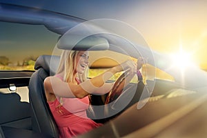 Happy young woman driving convertible car