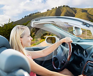 Happy young woman driving convertible car