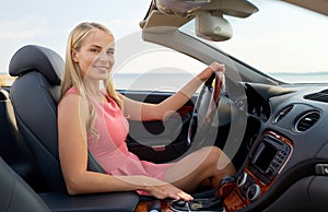 Happy young woman driving convertible car