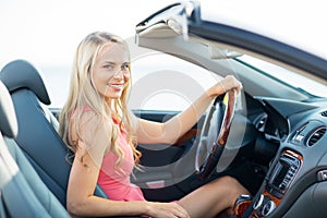 Happy young woman driving convertible car