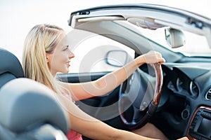 Happy young woman driving convertible car