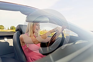 Happy young woman driving convertible car