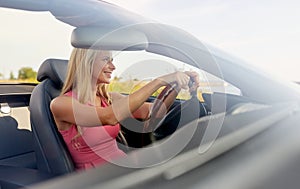 Happy young woman driving convertible car