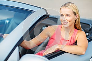 Happy young woman driving convertible car