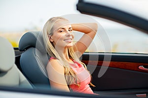 Happy young woman driving convertible car