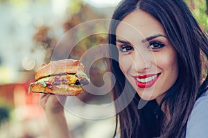 Happy young woman eat tasty fast food burger