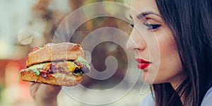 Happy young woman eat tasty fast food burger