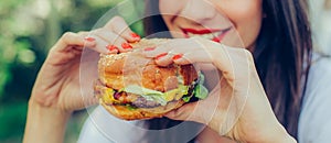 Happy young woman eat tasty fast food burger