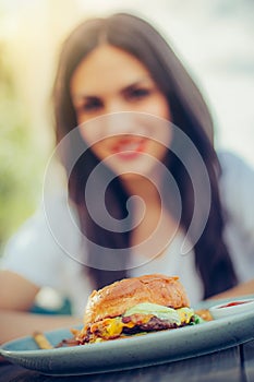 Happy young woman eat tasty fast food burger