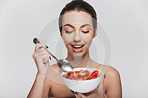 happy young woman eating cereal breakfast with strawberries