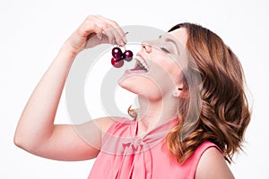 Happy young woman eating cherry