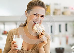 Feliz mujer joven comer crujiente pan en La cocina 