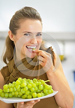 Happy young woman eating grape