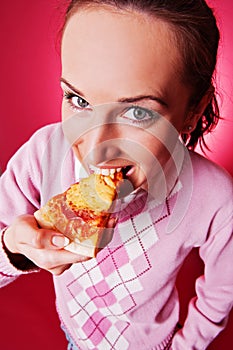 Happy young woman eating piece of pizza