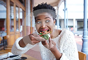 Happy young woman eating pizza at restaurant