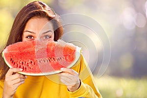 Happy young woman eating watermelon in the park