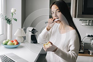 Happy young woman eats a piece of apple. Girl holds a knife near her mouth.