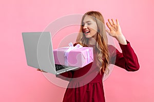 Happy young woman in an elegant red dress with a gift box celebrates Valentine's Day online