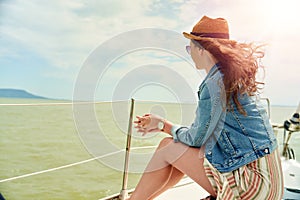 Happy young woman enjoying cruising on sailboat on a sunny cloudy summer day