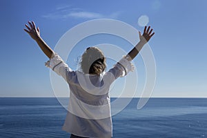 a happy young woman enjoying freedom with her hands open at sea