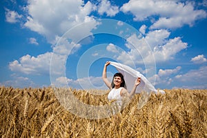 Happy young woman enjoying life in golden wheat field