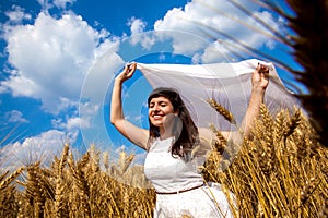 Happy young woman enjoying life in golden wheat field