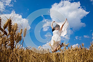 Happy young woman enjoying life in golden wheat field