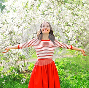 Happy young woman enjoying smell in flowering spring garden