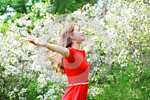 Happy young woman enjoying smell in flowering spring garden