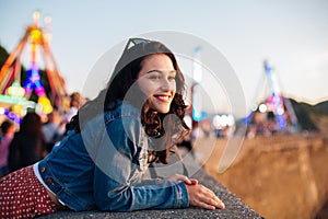 Happy young woman enjoying the sunset at fun fair in summer