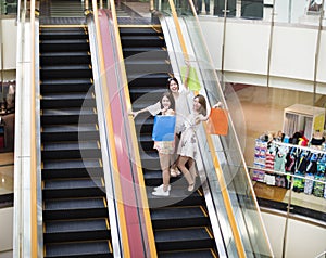 Happy young woman on escalator in shopping mall