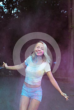 Happy young woman with exploding dry paint celebrating Holi fest