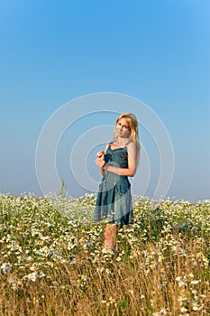 The happy young woman in the field of camomiles.Portrait in a sunny day