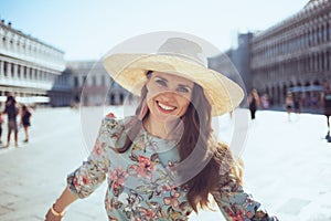 Happy young woman in floral dress with hat having walking tour photo