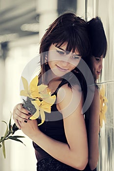 Happy young woman with flowers at the wall