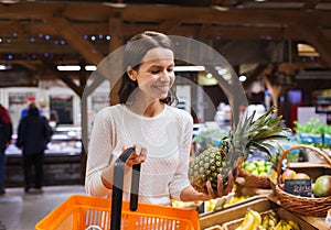 Happy young woman with food basket in market