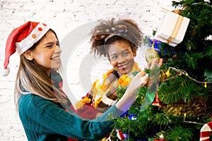 Happy young woman and friends decorating and preparation ornament on Christmas tree with enjoy together.